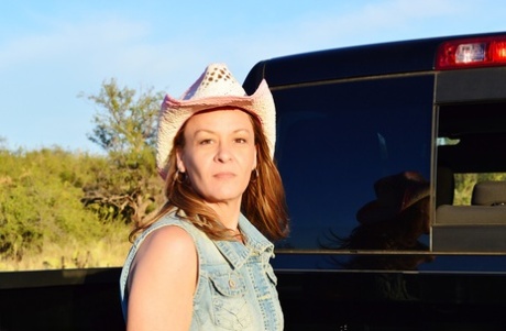 Mature cowgirl Emily Rain lifts her skirt up and shows her meaty pussy outside